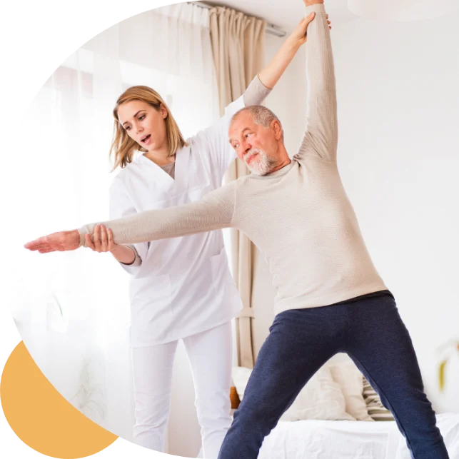 A healthcare professional assisting an older man with a stretching exercise in a bright room.